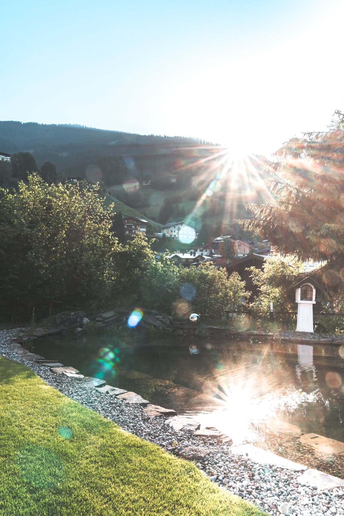 Gartenteich im Sommer bei Sonnenschein mit Blick auf die Berge, Naturbadeteich, Sommerurlaub in den Bergen