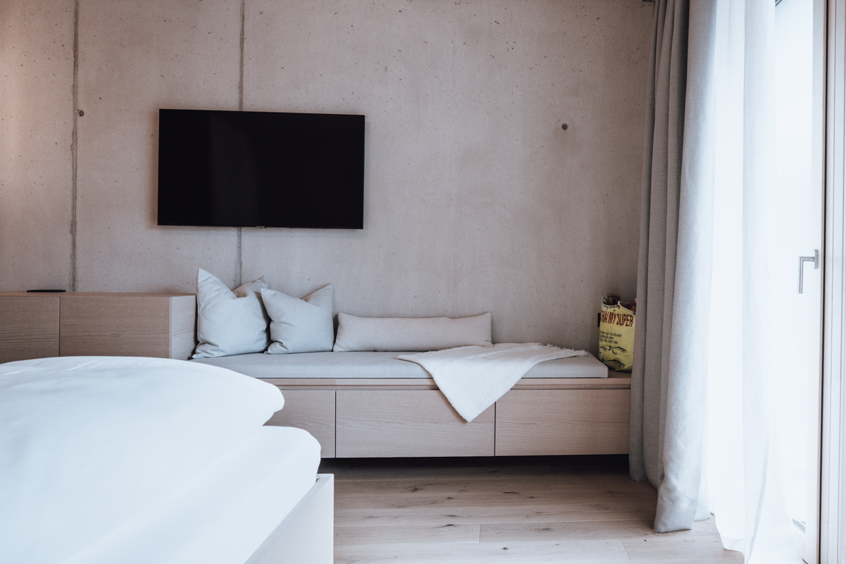 Hotel_HausJausern_Avantgardist Design Hotelzimmer, Avantgardist, Zimmer mit Ausblick, Kunst, Winterurlaub in den Bergen, Sichtbetonwand mit gemütlicher Sitzecke, Holz, Naturmaterialien