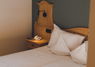 Das Design Doppelzimmer im Hotel Haus Jausern Saalbach.Massivholzbett, Daunenkissen und Kunst, der Individualist bietet eine tolle Ausstattung.