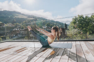 Frau in Sportkleidung beim Pilates auf einer Yogamatte auf dem Balkon