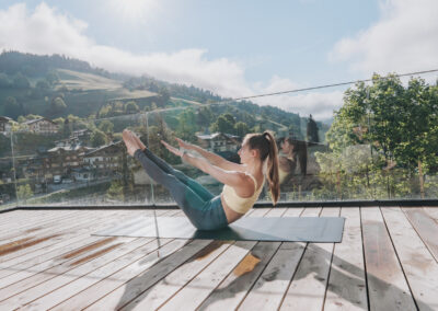 Frau in Sportkleidung beim Pilates auf einer Yogamatte auf dem Balkon